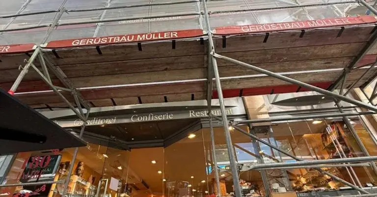 Geöffnetes Ladengeschäft von Printen Schmitz unter dem Schutzdach des Fassadengerüsts an der Breite Straße in Köln