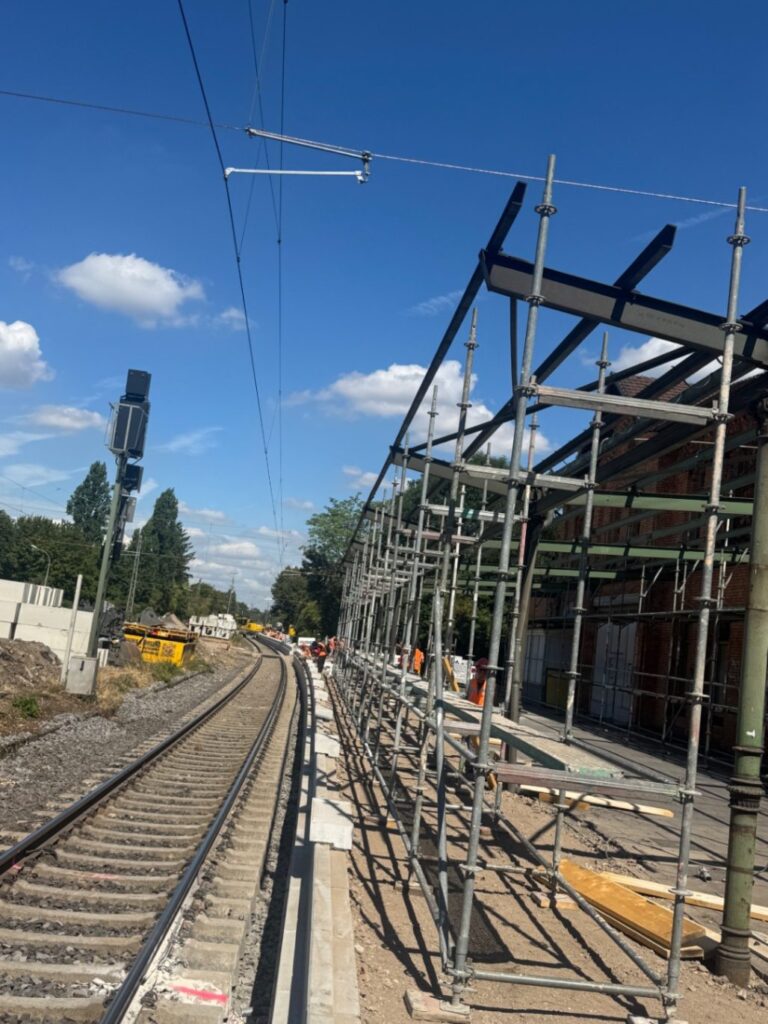 Wetterschutzdach am Bahnhof Niederdollendorf: Gerüstreihe entlang des Gleises bei laufendem Bahnbetrieb