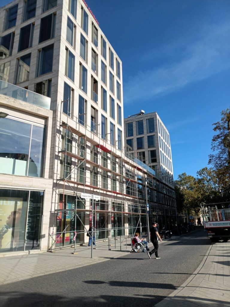 Passanten gehen am Fassadengeruest des AUREUM in der Bonner Innenstadt vorbei, Bauabschnitt 2 im Aufbau